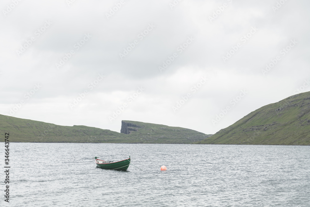 Morning view on lonely boat on cloudy Sorvagsvatn lake on cliffs of Vagar island, Faroe Islands, Denmark. Landscape photography
