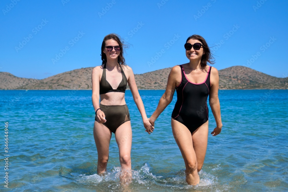Mother teen daughter daughter together on the beach, holding hands