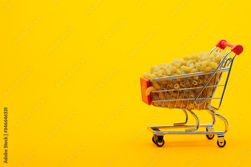 Grocery trolley filled with pasta on a bright orange background