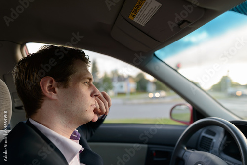 Profile view of young handsome businessman driving car in suburban street © Ranta Images
