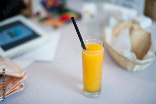 Orange drink, tablet and bread basket laid on table in cafe. Shallow depth of field.