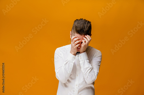 Funny handsome man fools around. Making crazy emotions. Caucasian man wears white shirt and butterfly. Isolated orange backround. On-line work at home quarantine concept