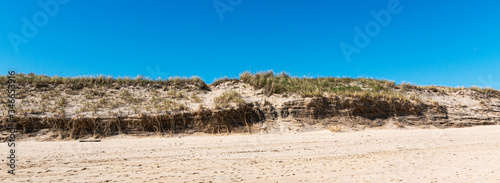 Battered sand dune with blue sky on Montauk beach Long Island photo