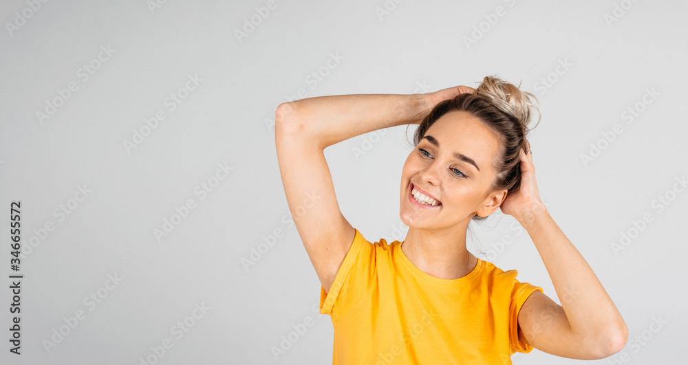 Beautiful young woman smiling against white background, hands in the hair, looking to the side, copy space Beautiful young woman smiling against white background, hands in the hair, looking to the side, copy space