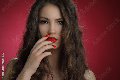 Attractive woman with nails and make up on red background
