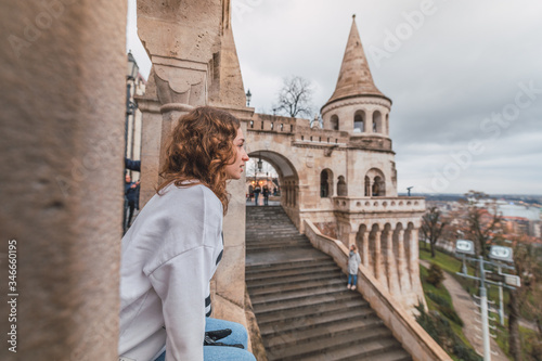 Photography Young woman sitting in the Fisherman's Bastion overlooking the city of Budapest,