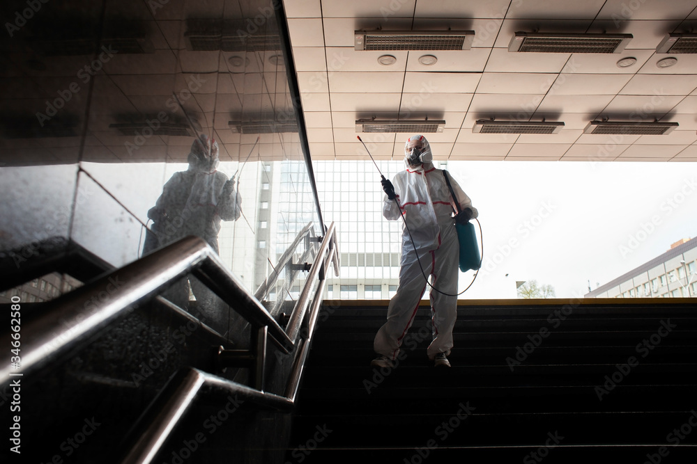 disinfection of the city from coronavirus, a man in a protective suit and respirator cleans the handrails of the stairs with a chemical spray, a sanitary worker disinfection of the city from coronavirus, a man in a protective suit and respirator cleans the handrails of the stairs with a chemical spray, a sanitary worker