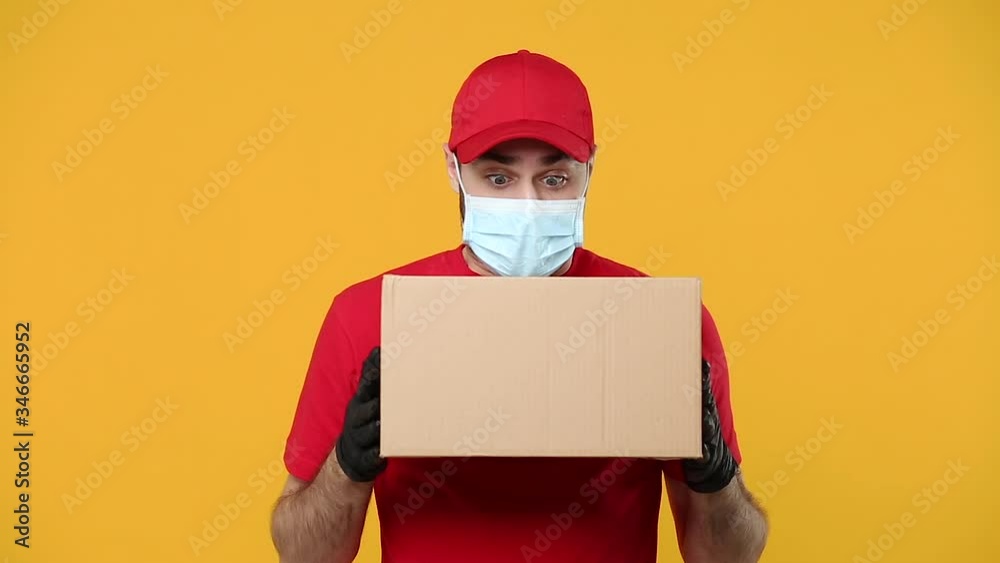 Delivery man employee in red cap blank t-shirt uniform face mask glove hold empty cardboard box isolated on yellow background studio Service quarantine pandemic coronavirus flu virus covid-19 concept Delivery man employee in red cap blank t-shirt uniform face mask glove hold empty cardboard box isolated on yellow background studio Service quarantine pandemic coronavirus flu virus covid-19 concept