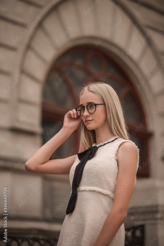 beautiful young girl blonde portrait, on a background of a white old building
