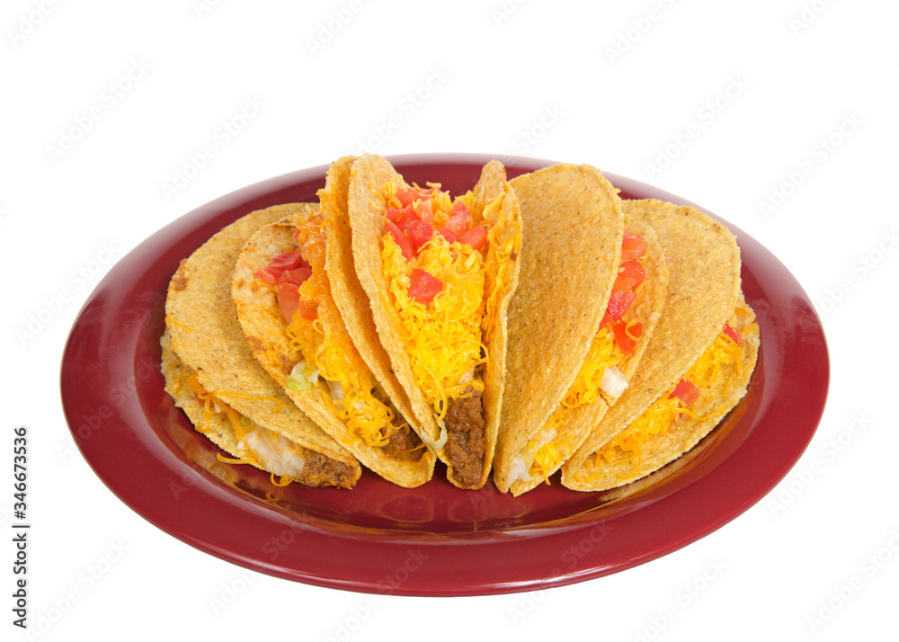 Five crispy tacos on a red plate isolated on white. Popular Americanized Mexican food. Viewed from above at an angle. Five crispy tacos on a red plate isolated on white. Popular Americanized Mexican food. Viewed from above at an angle.