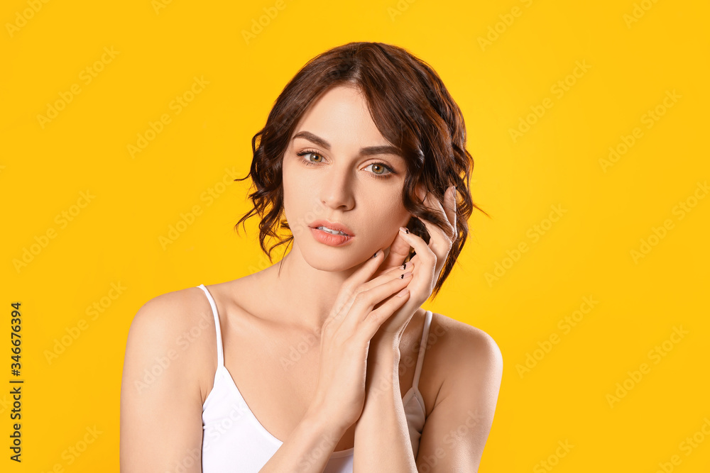 Obraz premium Young woman with beautiful short wavy hair on color background