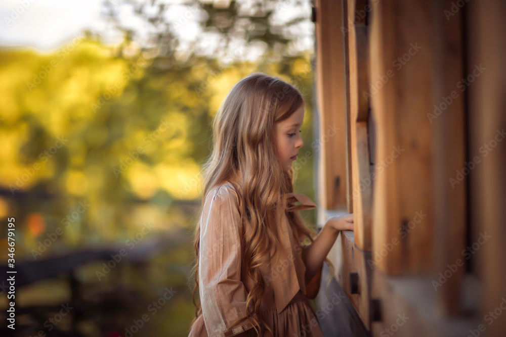 Fototapeta premium little girl with long blonde hair in a light dress on nature