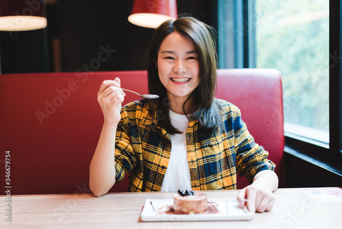 Young Asian woman was eating a dessert in cafe.