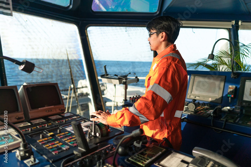 Fotografiet Filipino deck Officer on bridge of vessel or ship wearing coverall during navigaton watch at sea