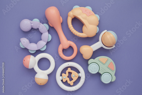 Flat lay composition with baby rattles set in pastel colors on lilac background.