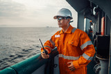 Filipino deck Officer on deck of vessel or ship , wearing PPE personal protective equipment. He holds VHF walkie-talkie radio in hands. Dream work at sea