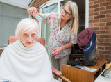 Elderly woman has hair cut by her carer during Corona virus lockdown at home.