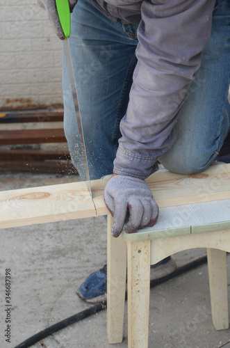 Close up of a man's hand sawing wood with a saw. Carpentry work