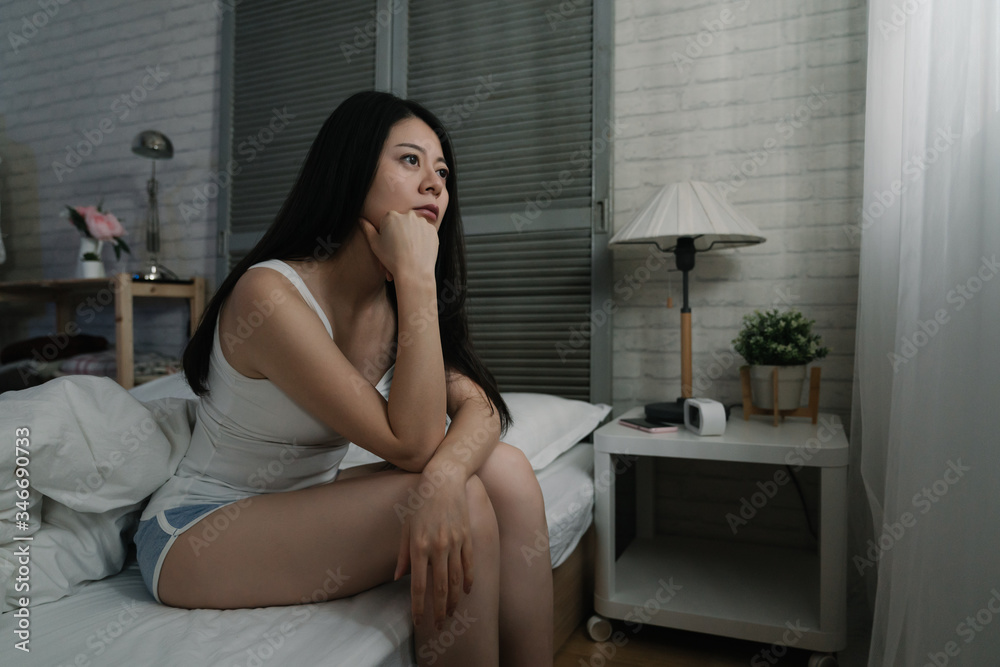 Devastated asian japanese woman crying sad feeling hurt and hopeless suffering depression. Depressed female victim of bullying sitting on bed alone in despair at night. young people mental health. Devastated asian japanese woman crying sad feeling hurt and hopeless suffering depression. Depressed female victim of bullying sitting on bed alone in despair at night. young people mental health.