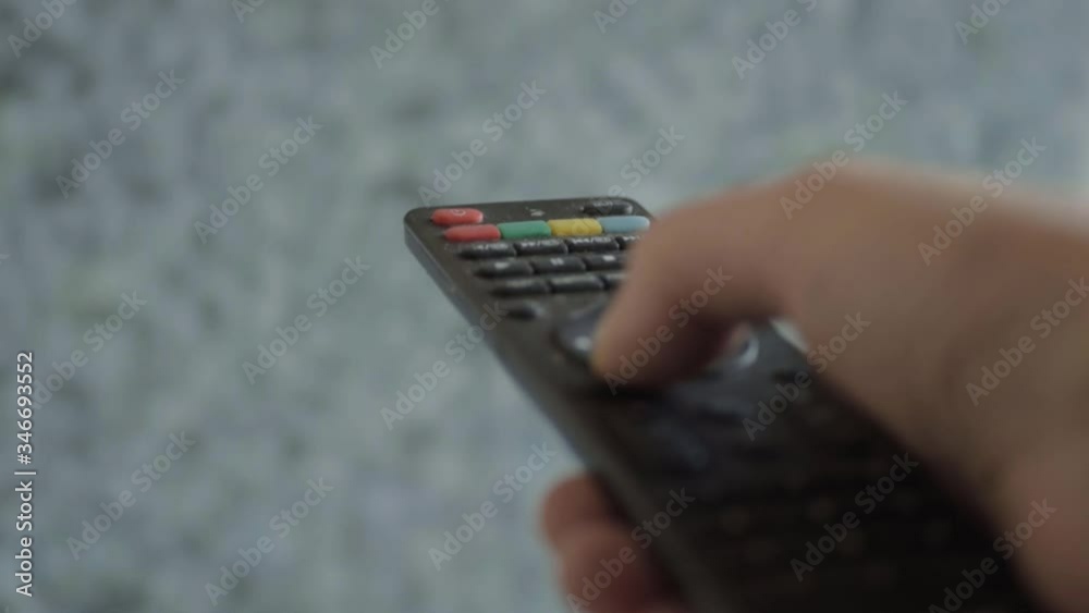Hand using remote control to change channel with static TV background close up shot Hand using remote control to change channel with static TV background close up shot