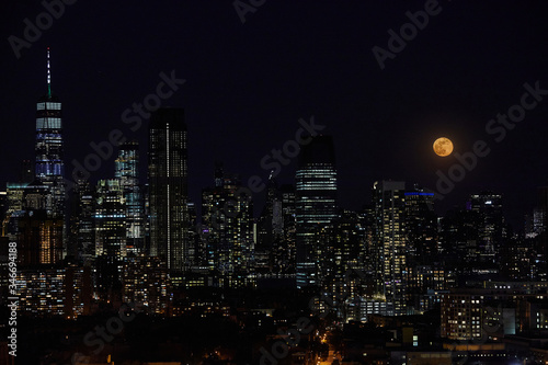 A full moon and night sky over a downtown city skyline.