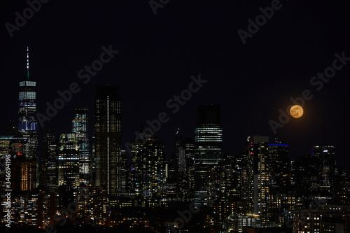 A full moon and night sky over a downtown city skyline. © Jodi
