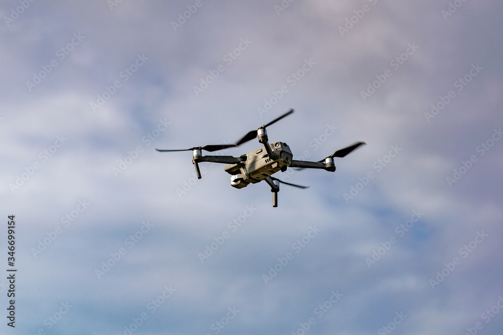 Drone with professional camera flying in the blue sky Drone with professional camera flying in the blue sky