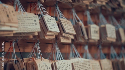 People and tourists visiting Kyakuden Meiji Shrine in Yoyogi park. Close up of message on wood label. Blurred temple in the background