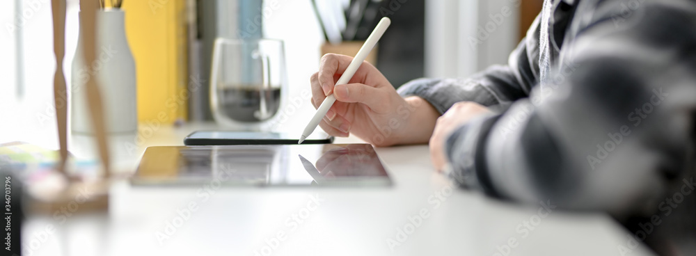 Side view of female graphic designer working on digital tablet on white worktable Side view of female graphic designer working on digital tablet on white worktable