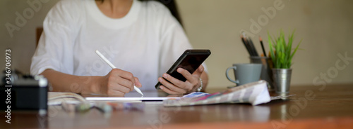 Cropped shot of female university student working on her project on wooden desk