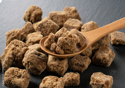 Shooting a brown sugar lump and a wooden spoon placed on a black background from an angle