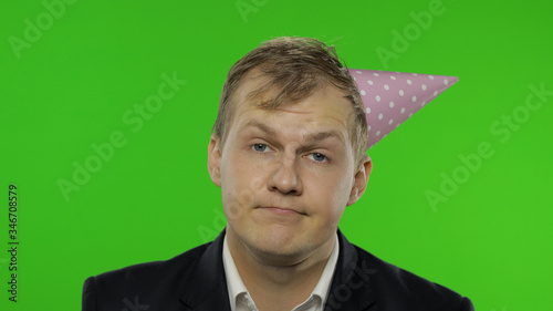 Drunk upset disheveled young businessman in festive cap. Hangover photo