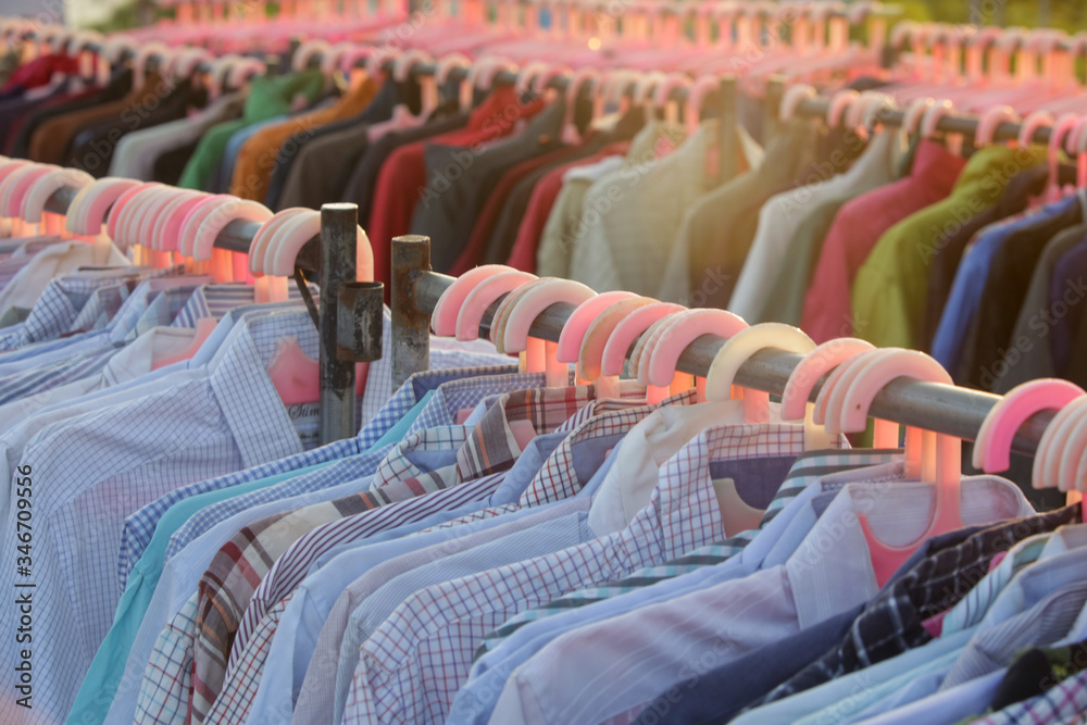 Fototapeta premium Huge selection of different used clothes for men, women and children on the rack in a second hand shop or thrift store. Concept of waste problem in fashion industry.