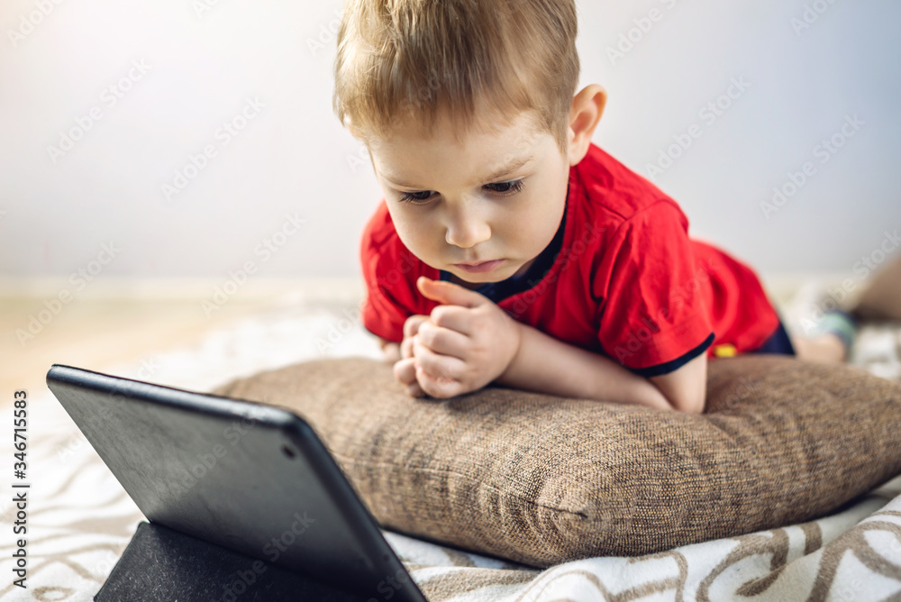 Preschool toddler child watches cartoons on a tablet on the internet. Gadgets and modern entertainment for children. Preschool toddler child watches cartoons on a tablet on the internet. Gadgets and modern entertainment for children.