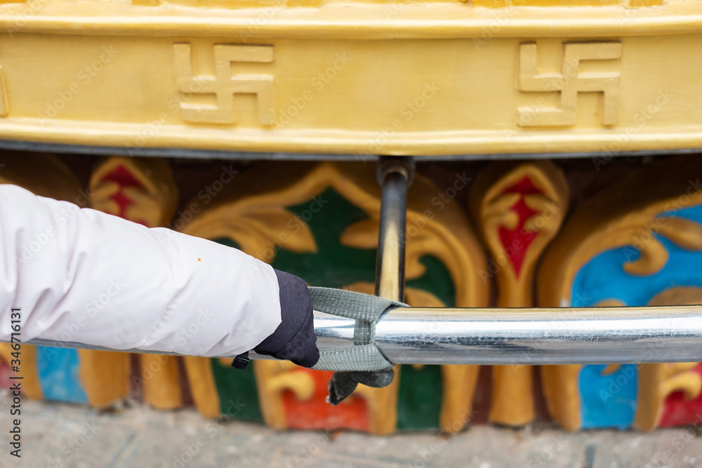 woman traveler hand spinning giant Golden Wheel in Shangri-La Golden temple or Dafo temple at Dukezong old town, Zhongdian,Yunnan. China. Asia travel concept