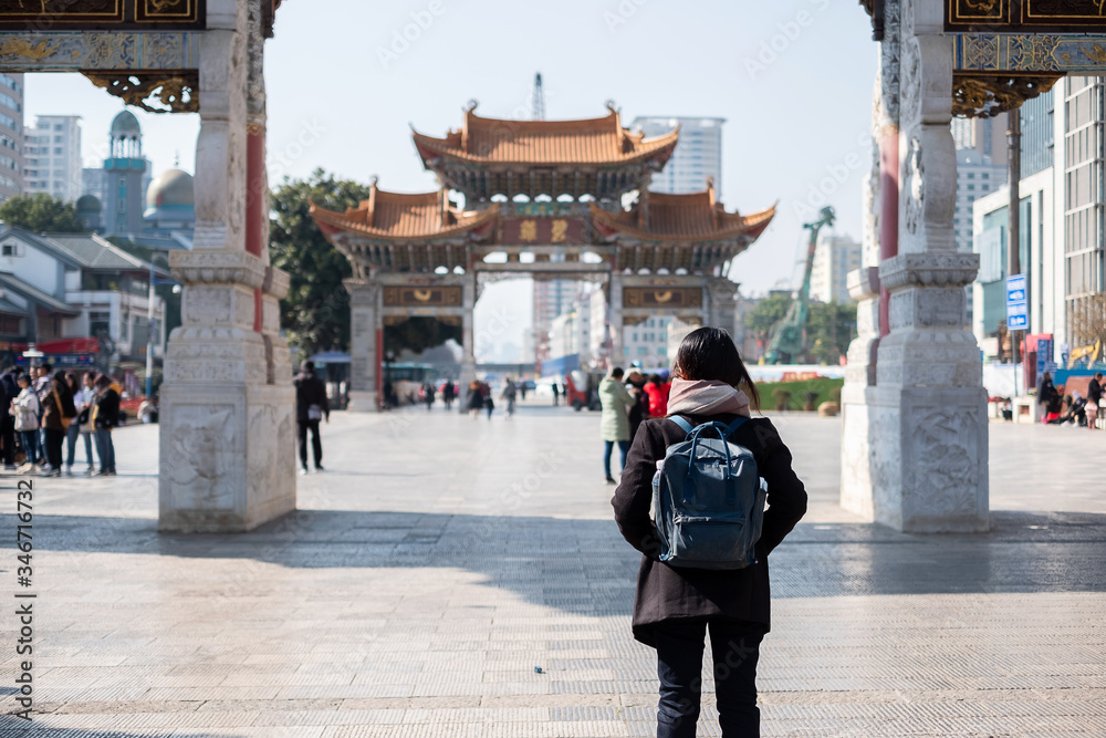 Young woman traveler traveling at Jinbi square, golden Horse and Jade Rooster Archways. landmark and popular for tourists attractions in Kunming, Yunnan, China. Asia and Solo travel concept