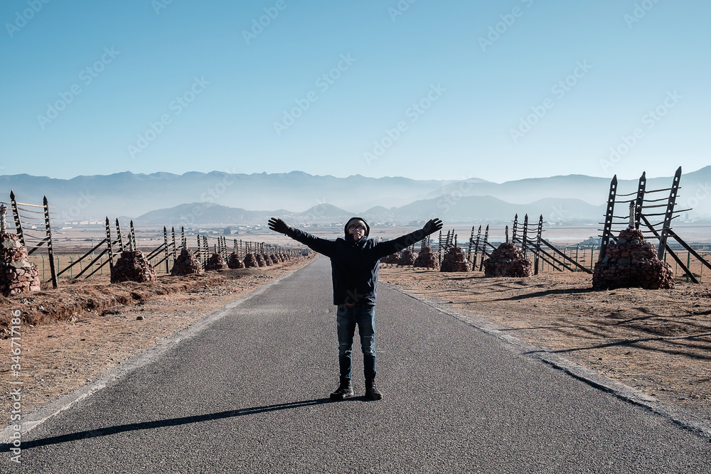 Φωτογραφία Young man traveler standing on road between going to Shika snow mountain with Tibetan stupa against mountains background
