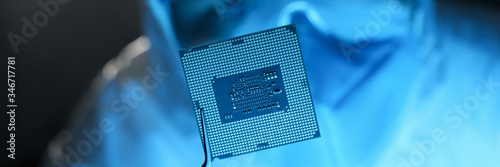 Картината върху платно Male hand in blue protective gloves with tweezers hold micro rocessor