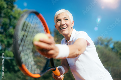 Smiling Elderly Woman Playing Tennis as a Recreational Activity © Microgen