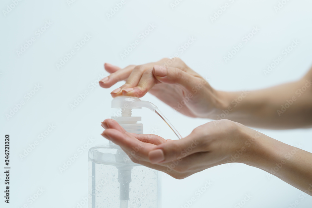 Plakat Hand with hand sanitizer in a clear pump bottle on a white background.