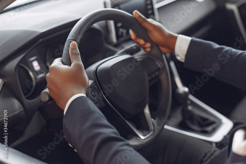 Man buying the car. Businessman in a car salon. Black male in a suit. © prostooleh