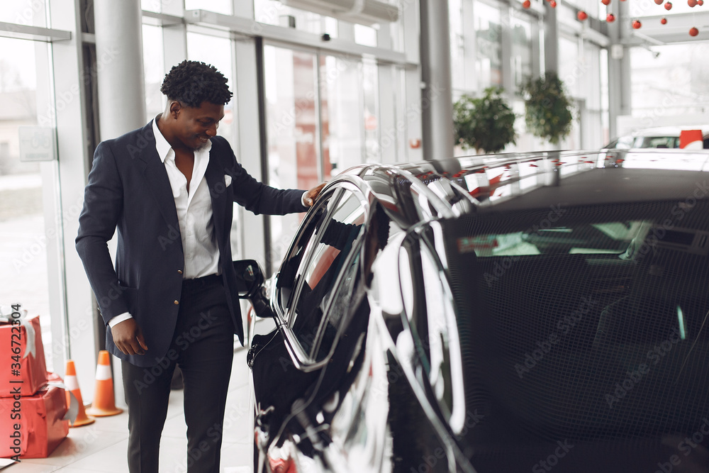 Man buying the car. Businessman in a car salon. Black male in a suit. Man buying the car. Businessman in a car salon. Black male in a suit.
