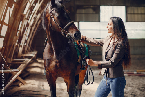 Fototapet Woman standing with a horse. Lady in a brown jacket