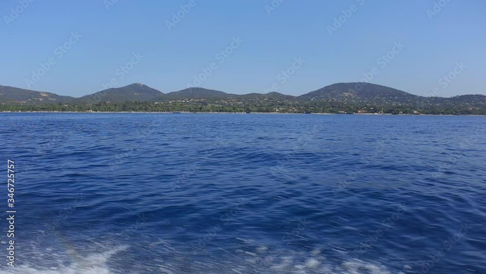sideways view on a boat looking at the water passing by as well as the shore covered in green mountains sideways view on a boat looking at the water passing by as well as the shore covered in green mountains