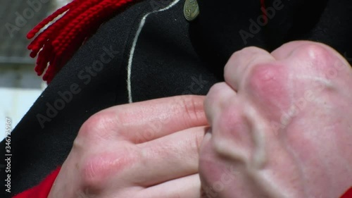 French Napoleon soldier closes the buttons of his costume. Close shot on hands. photo