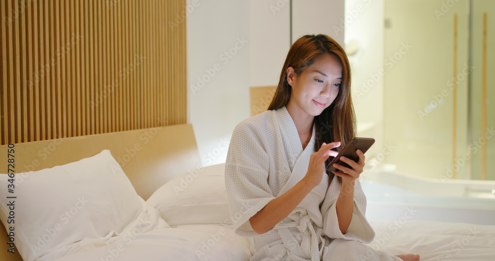 Woman uses smart phone on bed at night Woman uses smart phone on bed at night