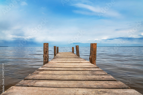 Perspective view of wooden pier at lake. Small bridge in water © FedBul