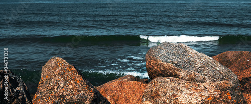 Large stones lie on the beach in front of the waves. photo