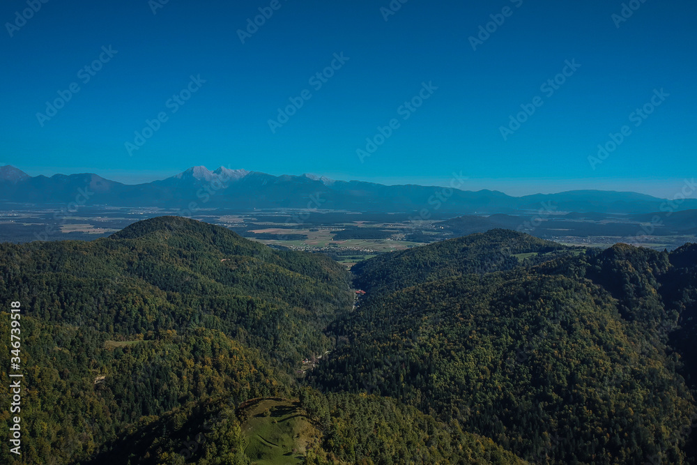 Panorama of a lonely farm with mountain hut on an open field in the hills or mountains of Govejk in Slovenia. Valley with forest and blue skies. Panorama of a lonely farm with mountain hut on an open field in the hills or mountains of Govejk in Slovenia. Valley with forest and blue skies.