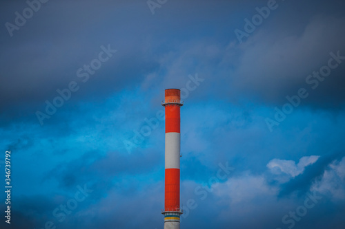 A tall single red and white chimney or smoke stack on a cloudy background Fototapeta